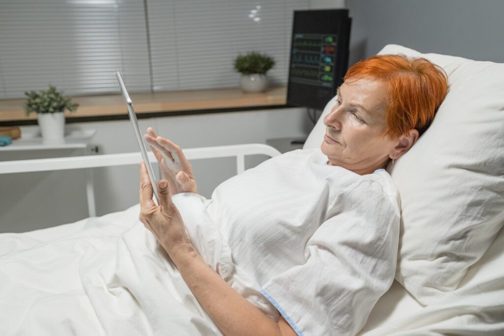 Ältere Frau benutzt Tablet-PC im Krankenhaus